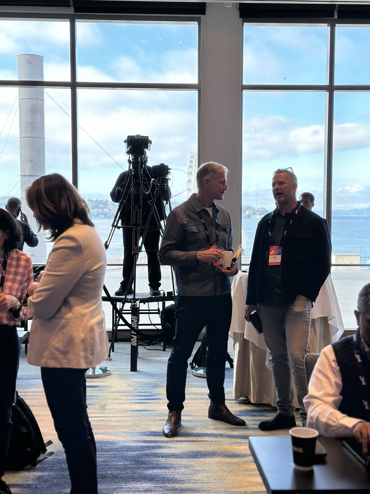 Attendees talking by the windows overlooking the waterfront