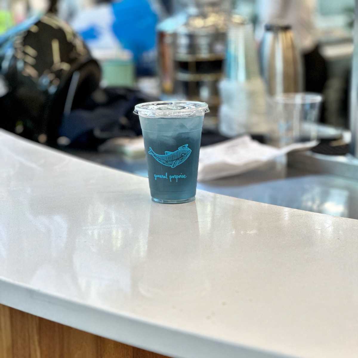 An iced blue drink with a whale illustration on a counter