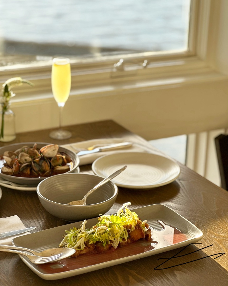 Seaside table with clams and a mimosa in golden-hour light