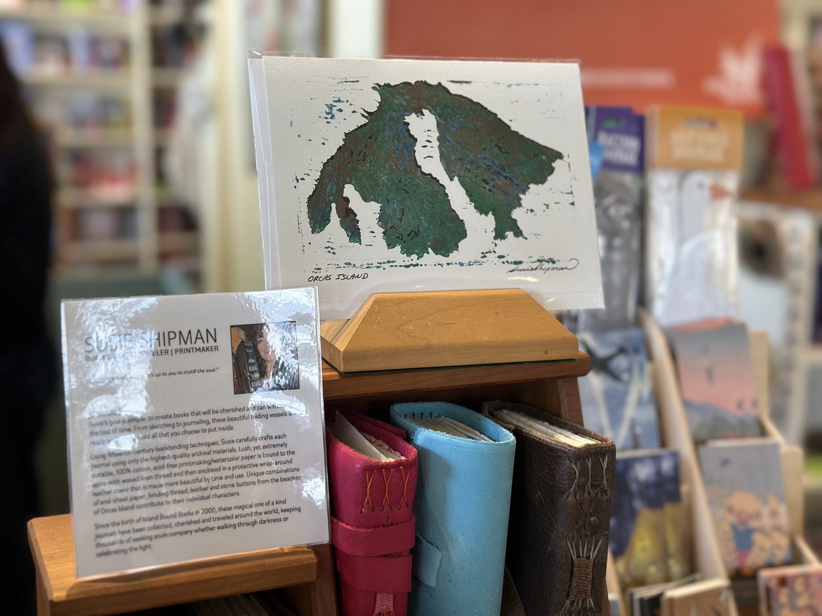A hand-printed Orcas Island card beside hand-bound leather journals
