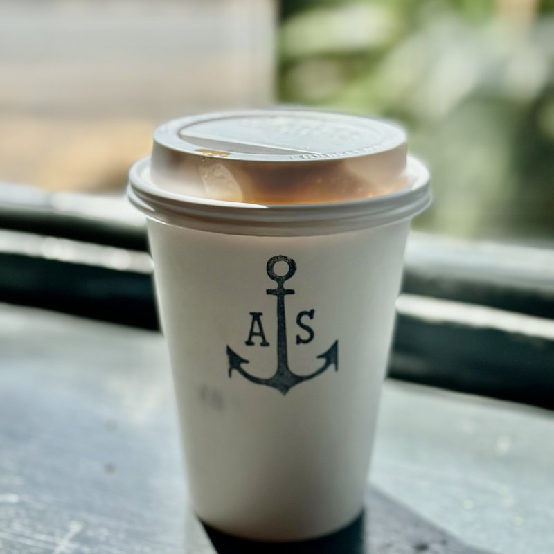 Anchor-stamped cup from Anchored Ship Coffee Bar, Ballard, on an outdoor caf&eacute; table