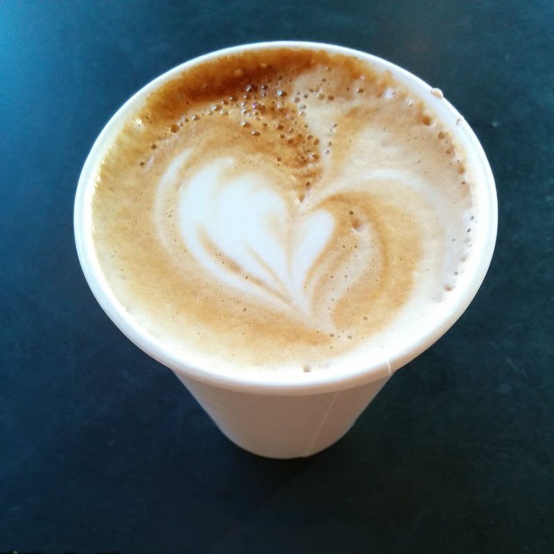 Heart latte in a paper cup on a black counter, 2014