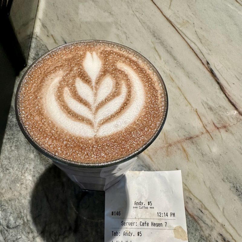 Tulip latte art beside a receipt reading Andy on veined marble