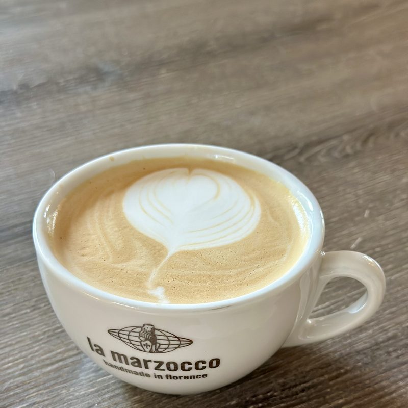 Heart latte in a La Marzocco cup on grey wood