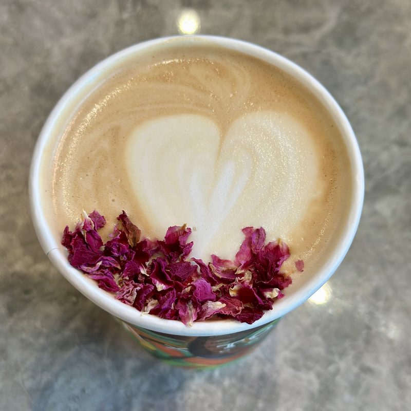 Heart latte art with rose petals on grey marble, cover frame of the Coffee collection.