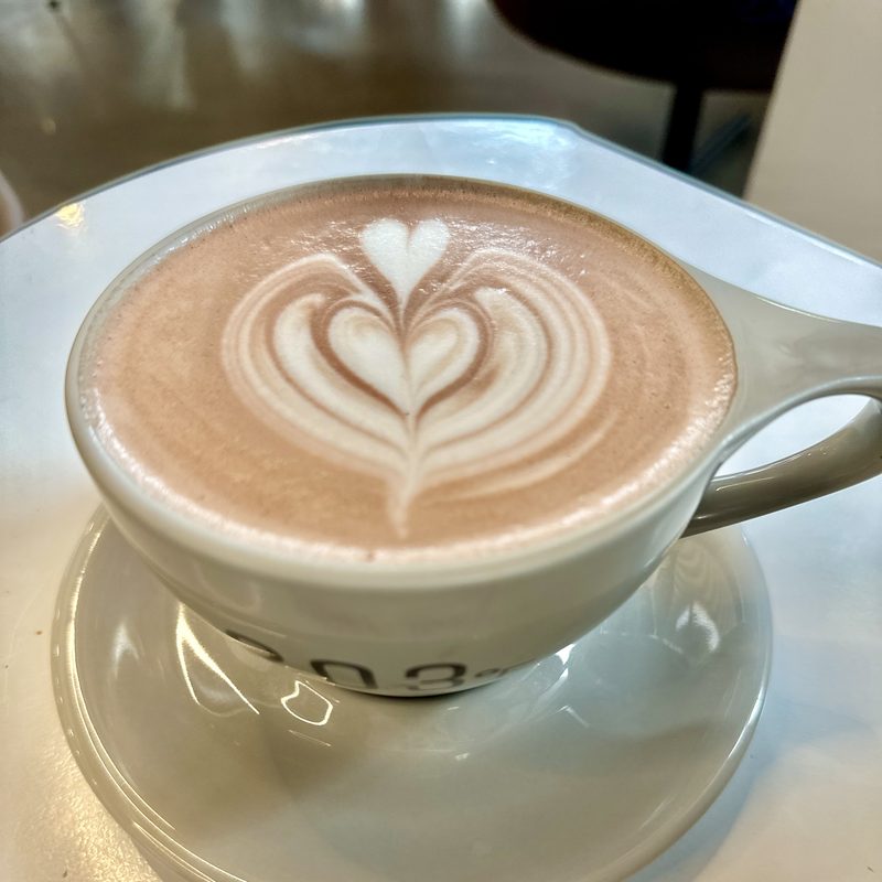 Stacked-heart mocha in a grey cup and saucer on a white table